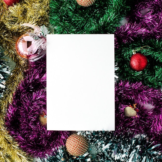 Empty paper blank and christmas decoration with colored glass balls, tinsel, toys. flat lay, top view