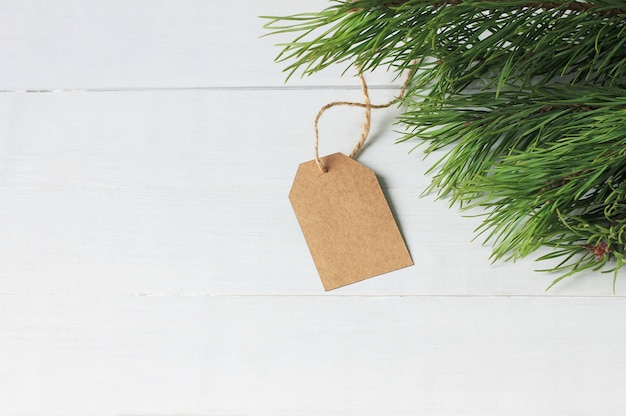 Empty paper price tag, spruce branches on wooden background