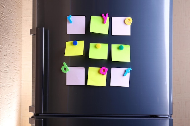 empty paper sheets and colorful magnets on fridge door