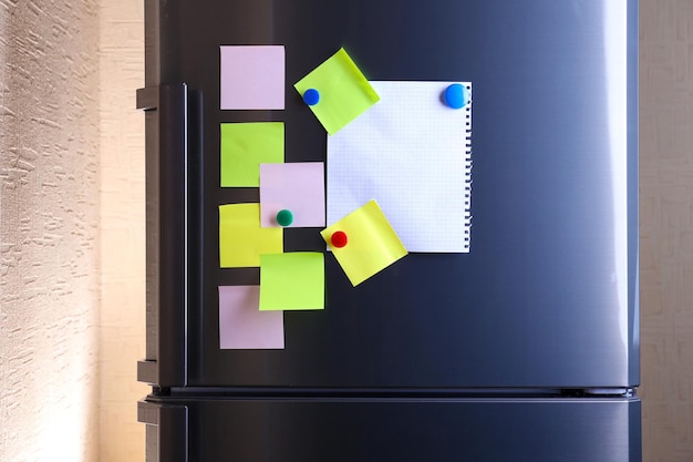 empty paper sheets and colorful magnets on fridge door