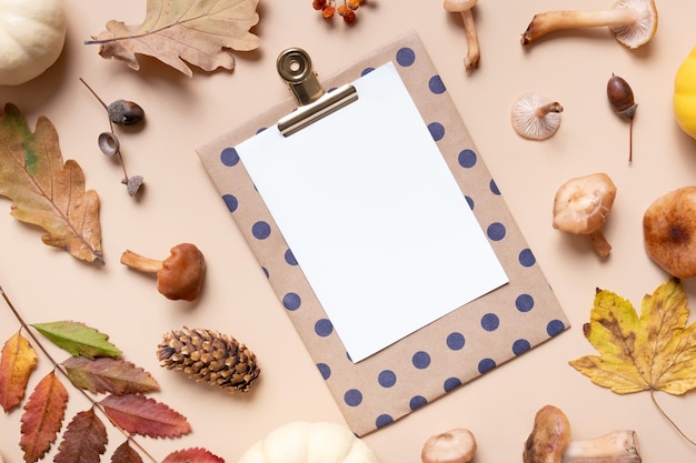 Empty paper with mushrooms and autumn leaves on beige background top view flat lay