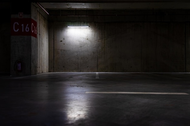 Empty parking lot with overhead dim light, underground parking garage.