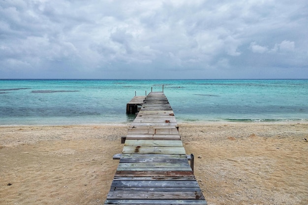 Empty pier on beach against sky