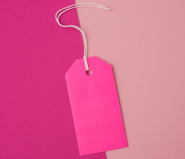 Empty pink paper rectangular tag on a rope on a colored background