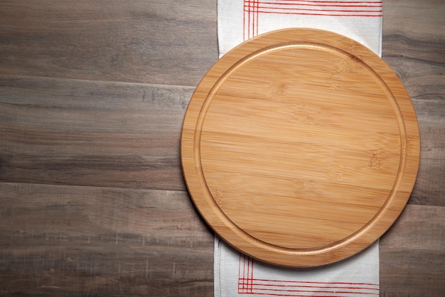 Empty pizza board and fabric tablecloth on the wooden background