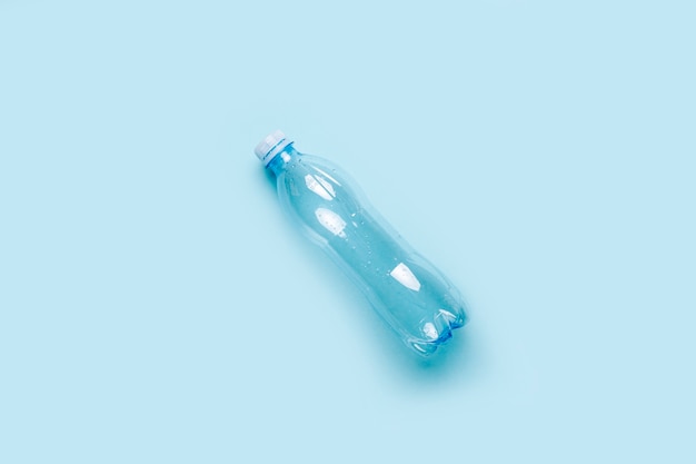 Photo empty plastic bottle on a blue surface. top view, copy space.