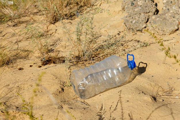 La bottiglia di plastica vuota si trova sulla sabbia