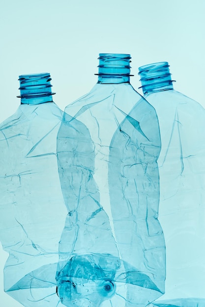 Empty plastic squashed bottles over blue background collecting plastic waste to recycling