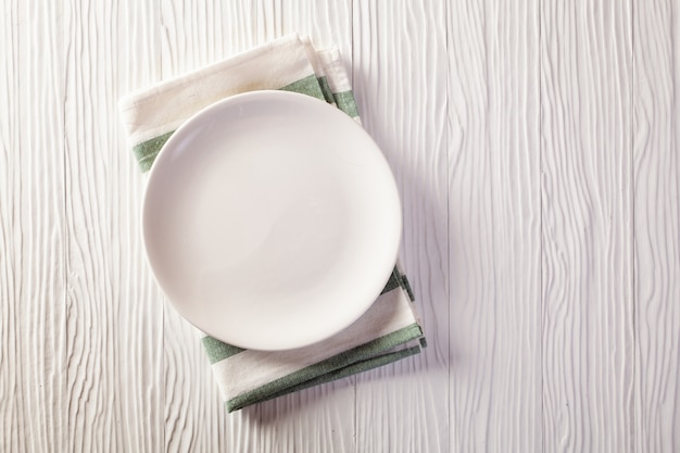 Empty plate on checkered tablecloth on white wooden table