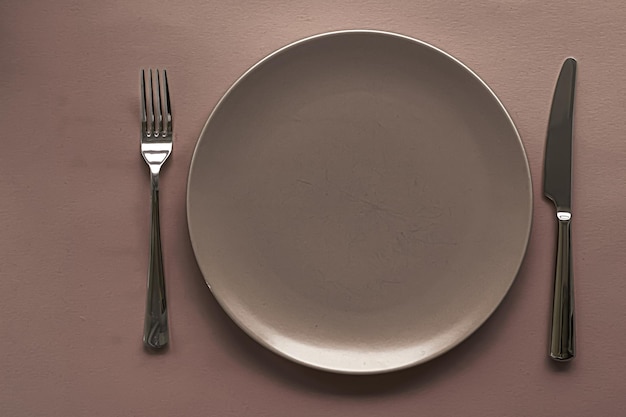 Empty plate and cutlery as mockup set on brown background top tableware for chef table decor and menu branding