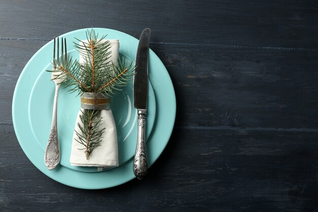 Empty plate, cutlery, napkin and glass on rustic wooden background. Christmas table setting concept