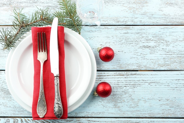 Empty plate, cutlery, napkin and glass on rustic wooden background. Christmas table setting concept