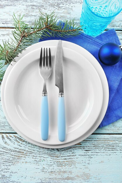 Empty plate, cutlery, napkin and glass on rustic wooden background. Christmas table setting concept