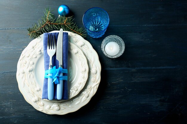 Empty plate, cutlery, napkin and glass on rustic wooden background. Christmas table setting concept