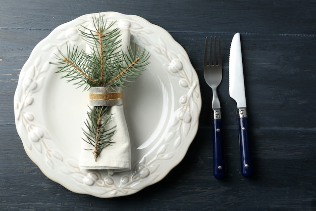 素朴な木製のテーブルに空の皿、カトラリー、ナプキン。クリスマステーブル設定の概念