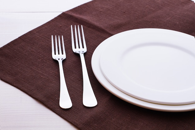 Empty plate, cutlery and napkin on wooden desk