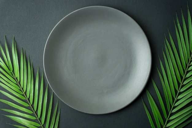 Empty plate on a dark background. Empty gray ceramic plate for food and dinner on a dark beautiful background.