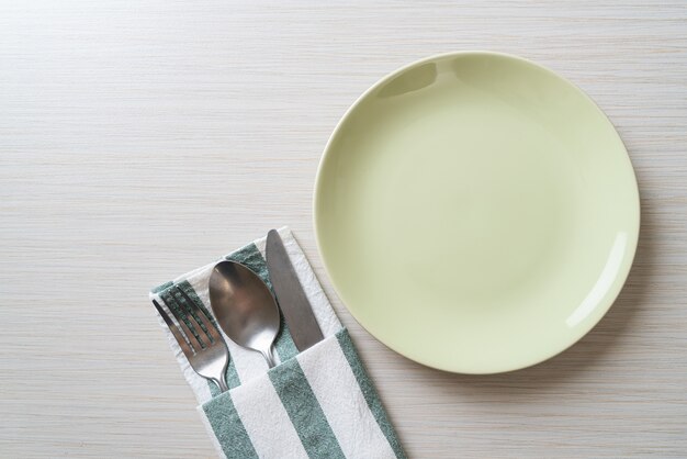 empty plate or dish with knife, fork and spoon on wood tile background