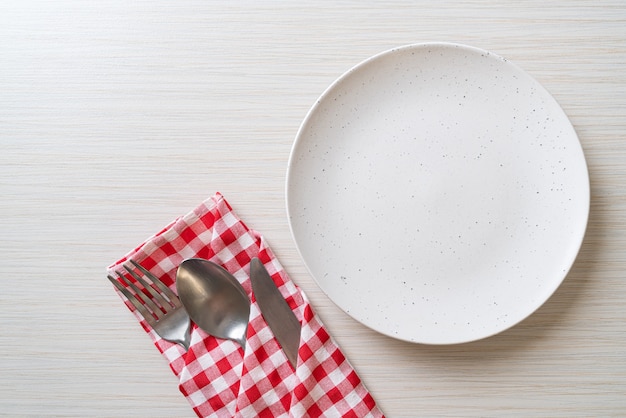 empty plate or dish with knife, fork and spoon on wood tile background