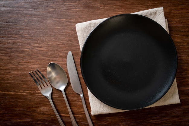 empty plate or dish with knife, fork and spoon on wood tile background