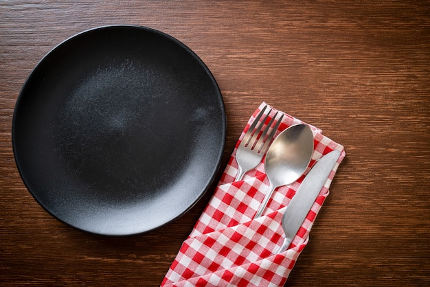 empty plate or dish with knife, fork and spoon on wood tile background