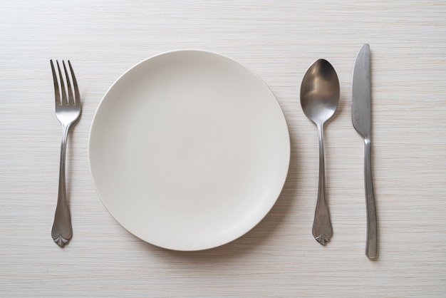 empty plate or dish with knife, fork and spoon on wood tile