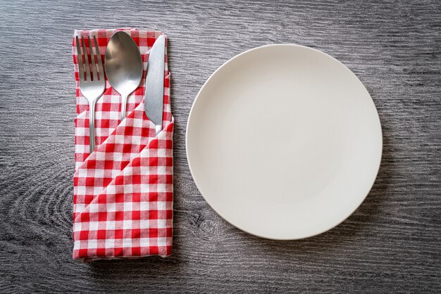 empty plate or dish with knife, fork and spoon on wood tile