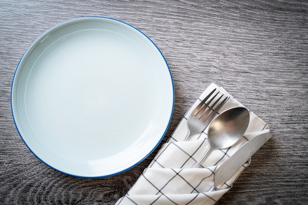 empty plate or dish with knife, fork and spoon on wood tile