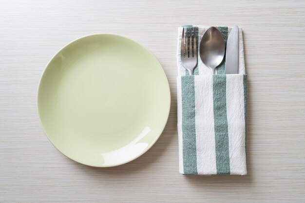 empty plate or dish with knife, fork and spoon on wood tile