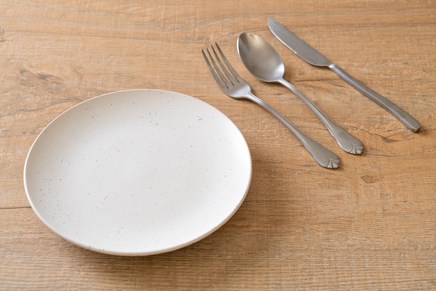 empty plate or dish with knife, fork and spoon on wood tile