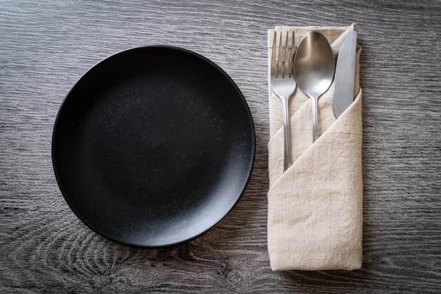 empty plate or dish with knife, fork and spoon on wooden board