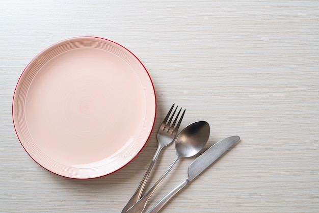 empty plate or dish with knife, fork and spoon on wooden table