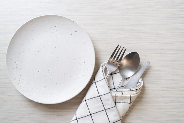 empty plate or dish with knife, fork and spoon on wooden table