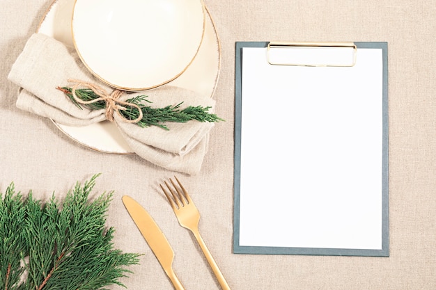 Empty plate and fir tree branches on linen table cloth in natural neutral colors. Flat lay, top view