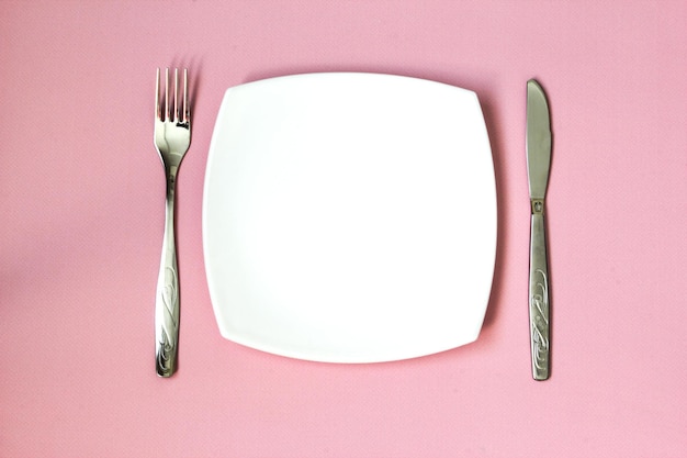 분홍색 배경 위에 빈 접시 포크와 나이프 밝은 배경에 깨끗한 접시와 수저