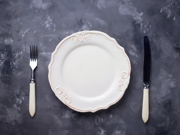 Empty plate and silverware on concrete table