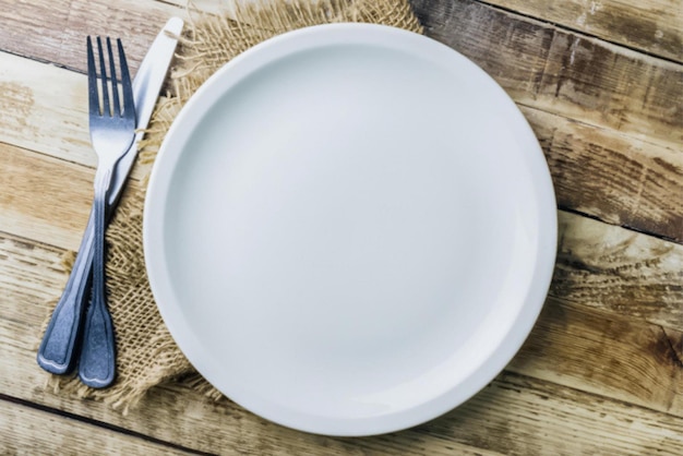 Empty plate spoon fork and knife on table Vintage silverware on rustic wooden background