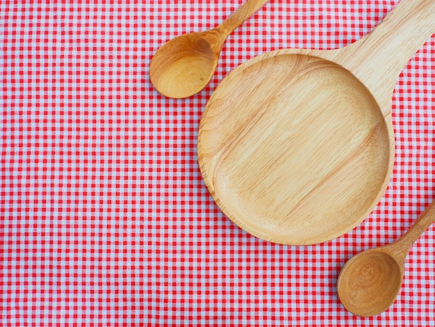 Empty plate and spoons on red checked tablecloth