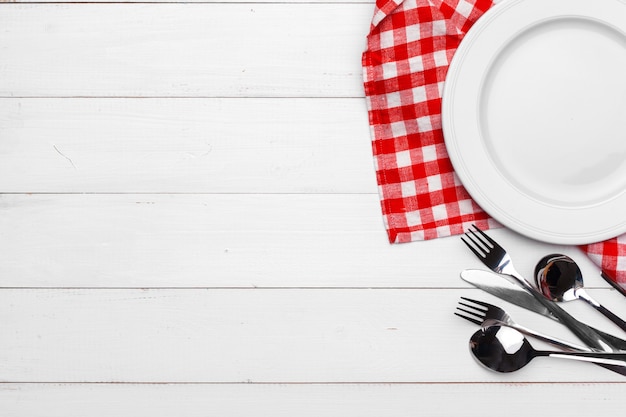 Empty plate and towel over wooden table background