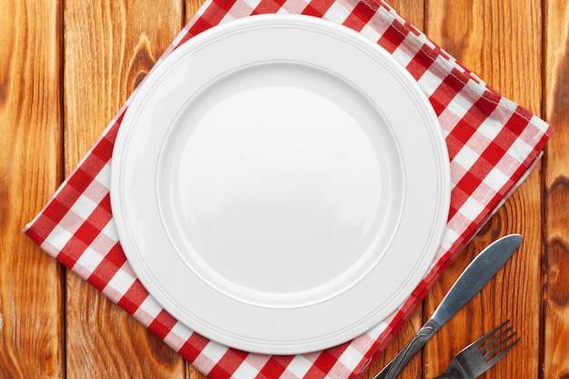 Empty plate and towel over wooden table 