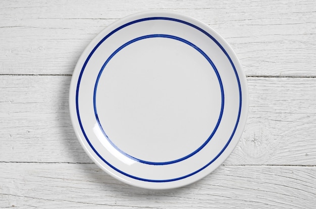 Empty plate on white wooden background, top view