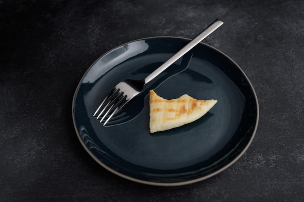 Empty plate with bitten off piece of bread and fork