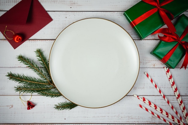 Empty Plate with Christmas decorations and fir tree on wooden background, flat lay