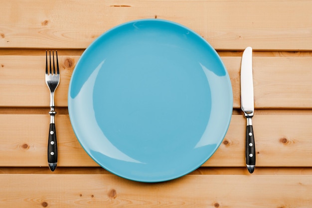 Empty plate with cutlery on a wooden table