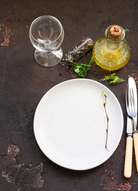 Empty plate with fork and knife on dark brown stone table