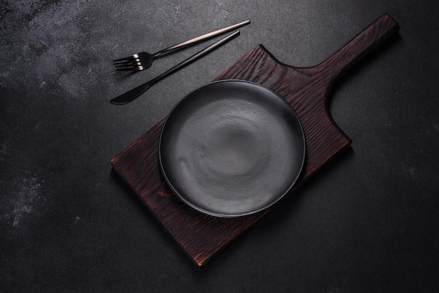 An empty plate with a knife fork or spoon with a wooden cutting board