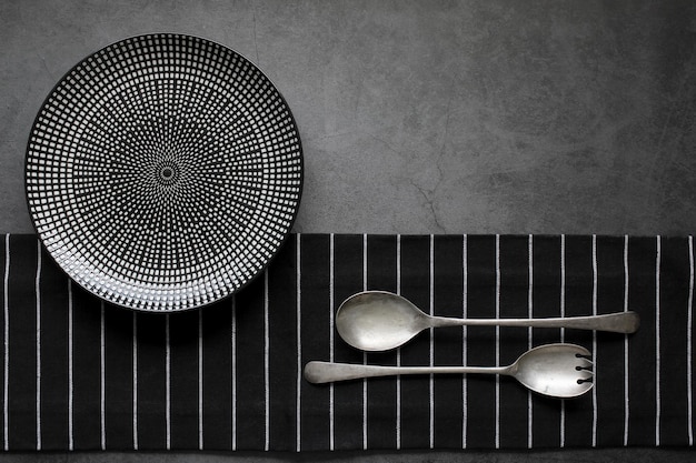 Empty plate with silver cutlery on the black background close up Restaurant menu concept template design Top view Copy space