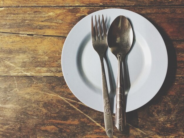 Empty plate with spoon and fork on table