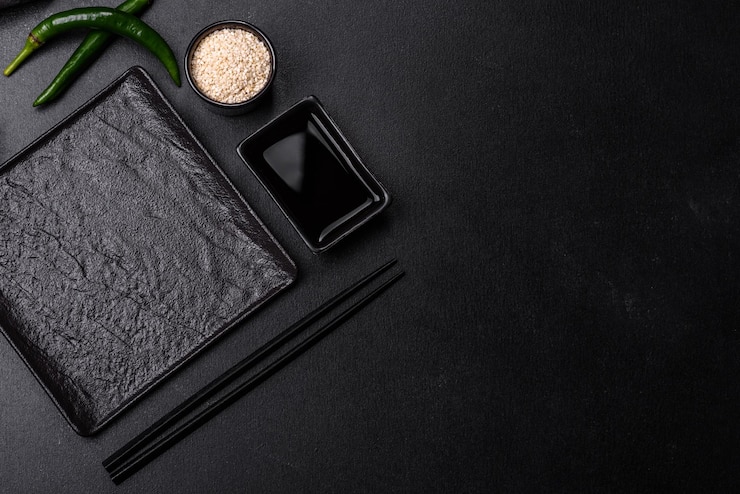 Photo empty plate with wooden sticks for asian food on a dark concrete background