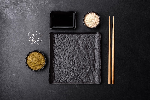 Empty plate with wooden sticks for Asian food on a dark concrete background